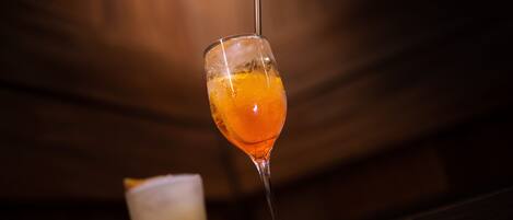 A glass of orange-colored drink with a straw, placed on a wooden surface.