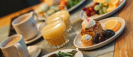 Una mesa de desayuno con diversos platos, como cruasanes, fruta y bebidas.