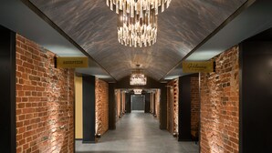 A reception area with a brick wall, a chandelier, and signs indicating reception and a restaurant. - Hotel Kakola (Turku)