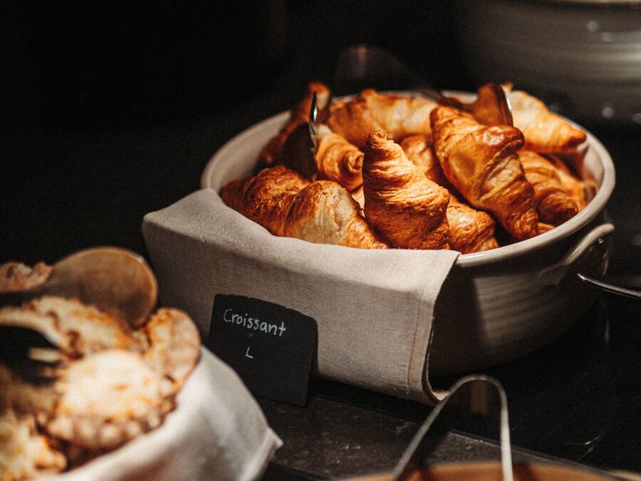 Un bufé con diversas opciones de panadería, incluyendo croissants y otros pasteles.