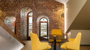 A dining area with yellow chairs, a round table, and brick walls. - Hotel Kakola (Turku)