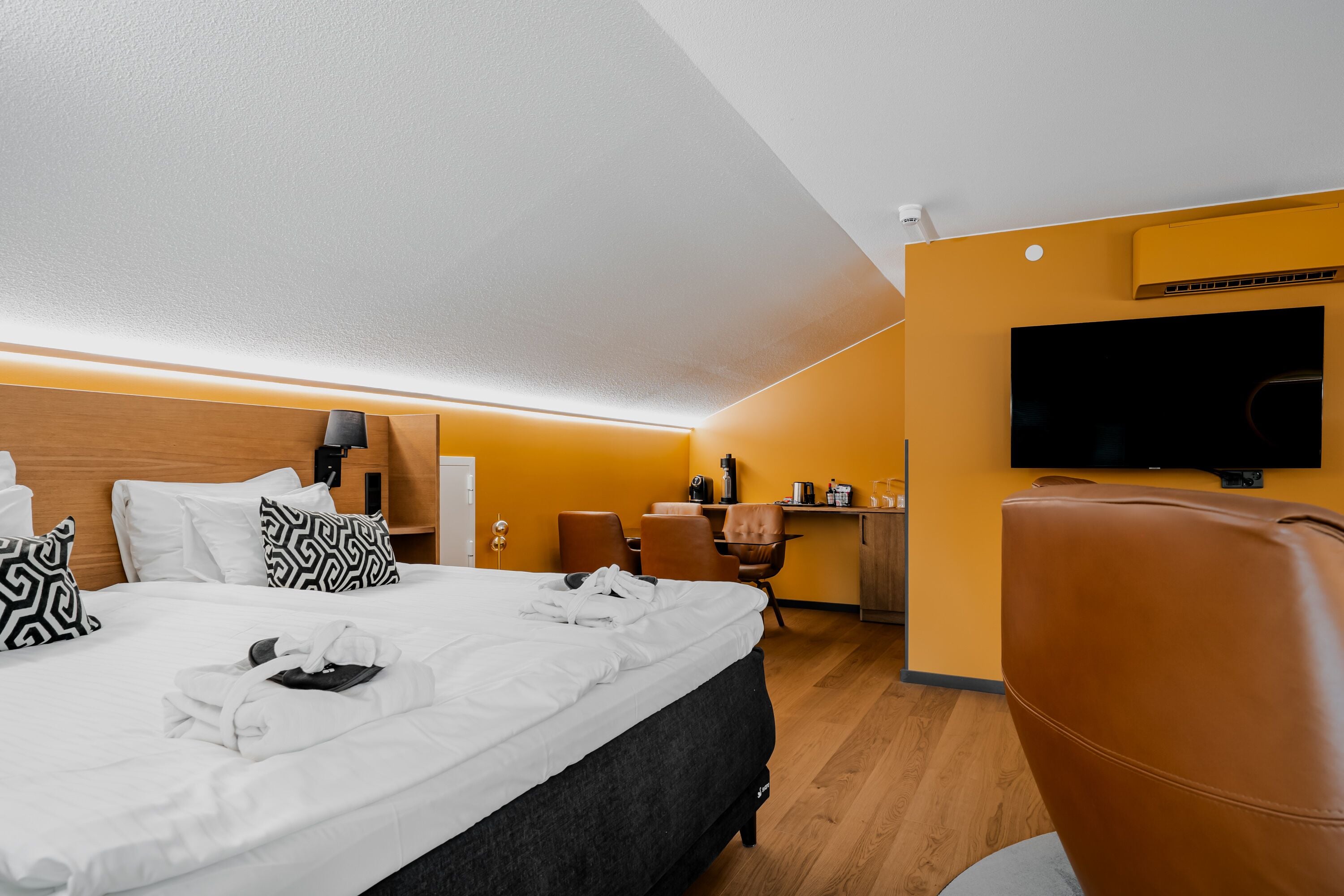 A hotel room with a bed, a desk, a chair, and a television.