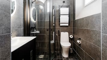 A modern bathroom with a glass-enclosed shower, a white toilet, and a sink with a mirror.