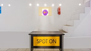A modern interior with a table labeled "SPOT ON" and a purple directional sign on the wall. - OYO 2277 Lulu Homes (Makassar)