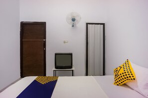 A room with a bed, a television on a small table, a wall fan, and two doors. - OYO 2277 Lulu Homes (Makassar)
