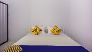 A hotel room with a bed, two pillows with a yellow and black design, and a blue and yellow patterned blanket. - OYO 2277 Lulu Homes (Makassar)