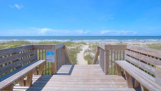 A wooden boardwalk leading to a beach with a clear sky. - Oceanfront 2BR condo in Caswell Beach, Oak Island—perfect for family getaways! (Oak Island)