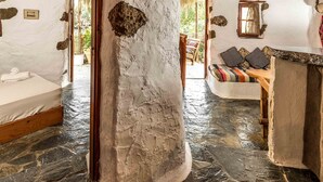 A rustic interior with stone walls, a wooden ceiling, and a stone floor. - Natura cottages (Sitia)