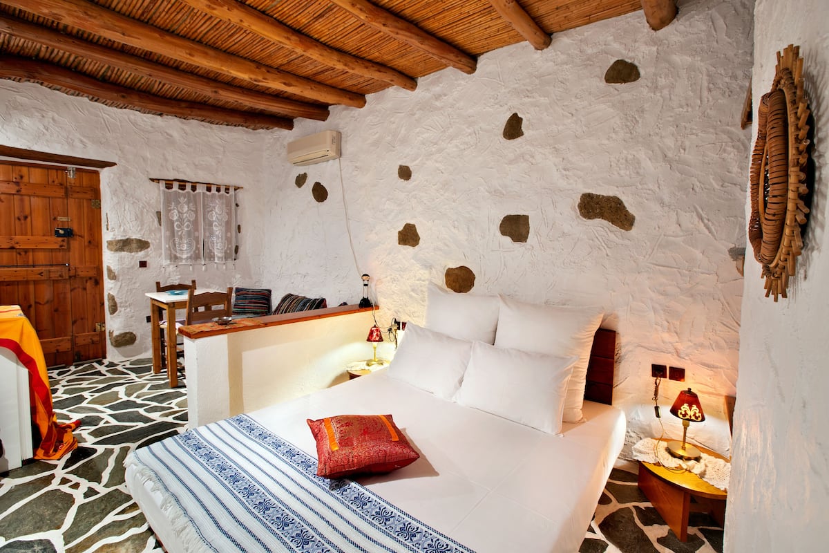Una habitación acogedora con una cama, una puerta de madera, una mesita y una lámpara.