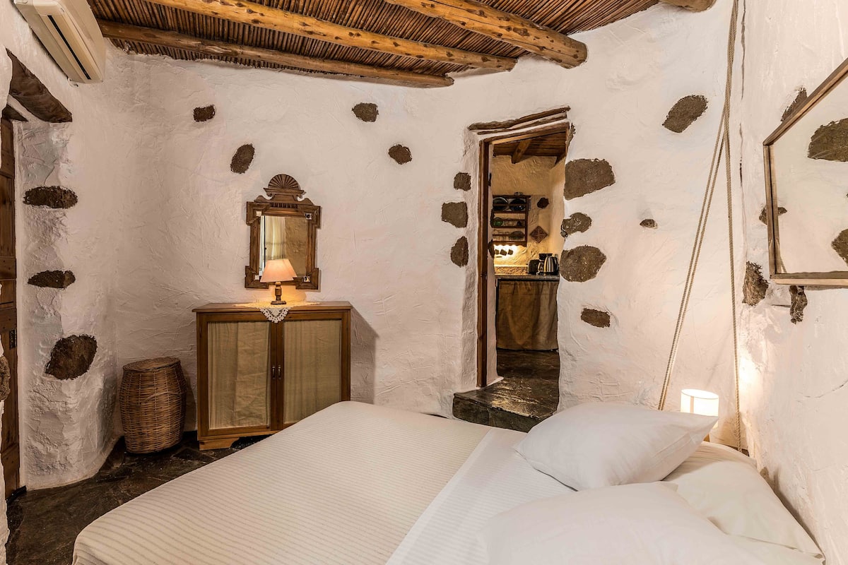 Un dormitorio rústico con cama, armario de madera y espejo.