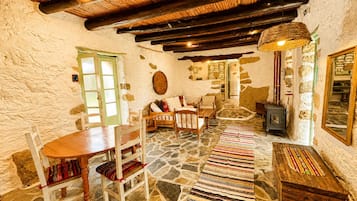 Un interior rústico con paredes de piedra, muebles de madera, suelo de piedra y un horno tradicional.