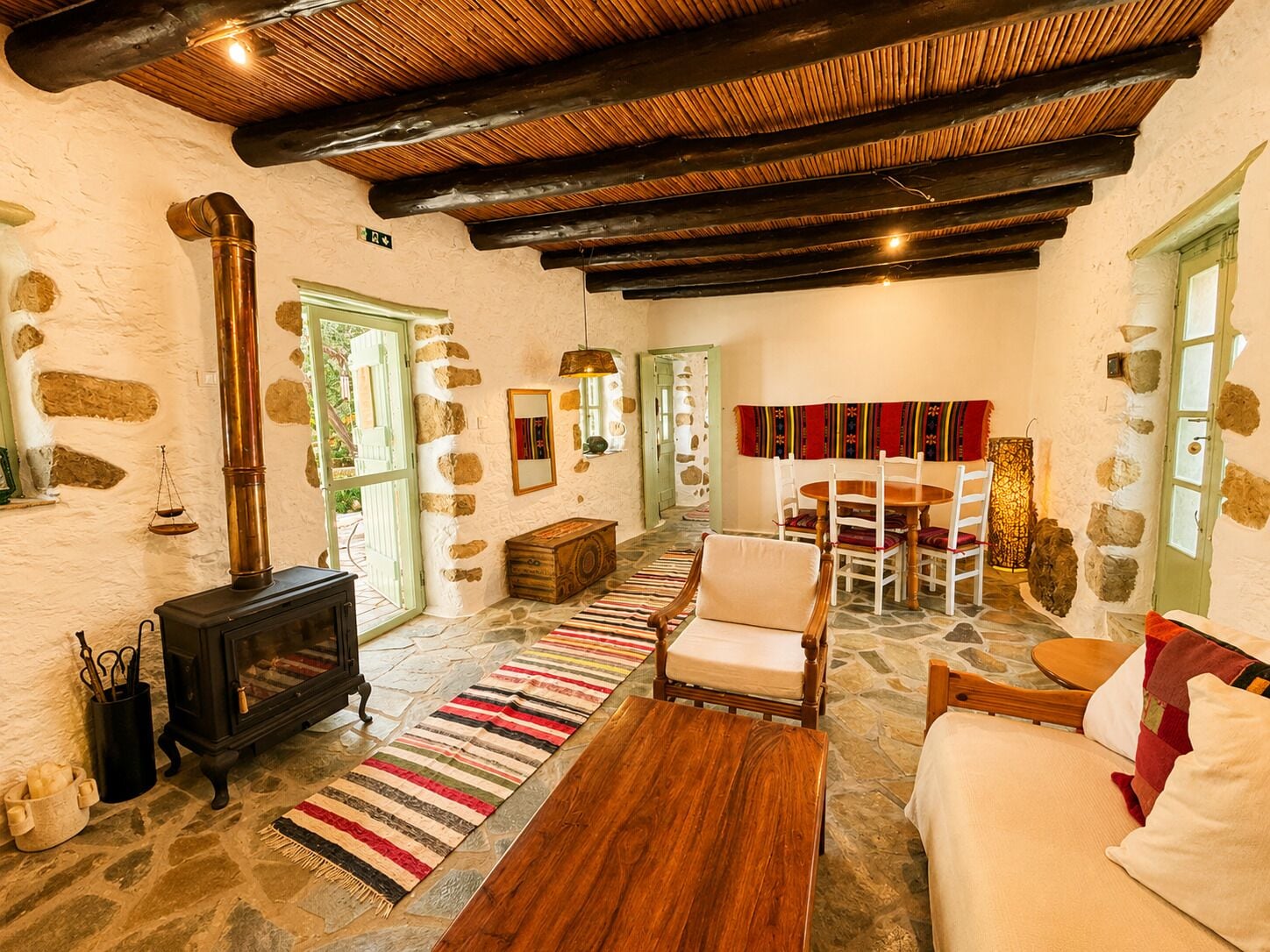 A rustic interior with stone walls, a fireplace, a dining area, and a cozy seating arrangement.