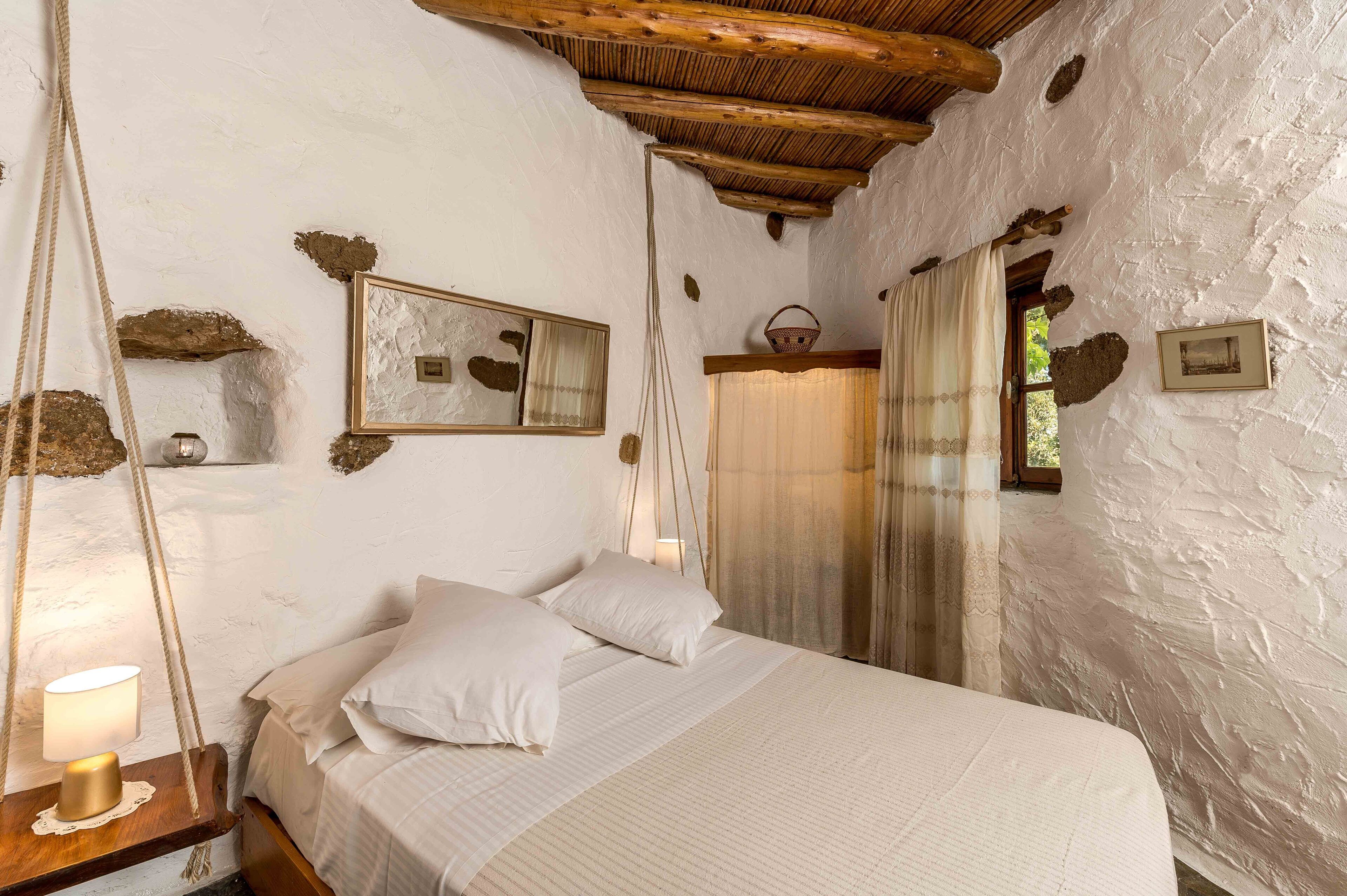 A rustic bedroom with a wooden bed, a hanging rope light, and a rustic ceiling.
