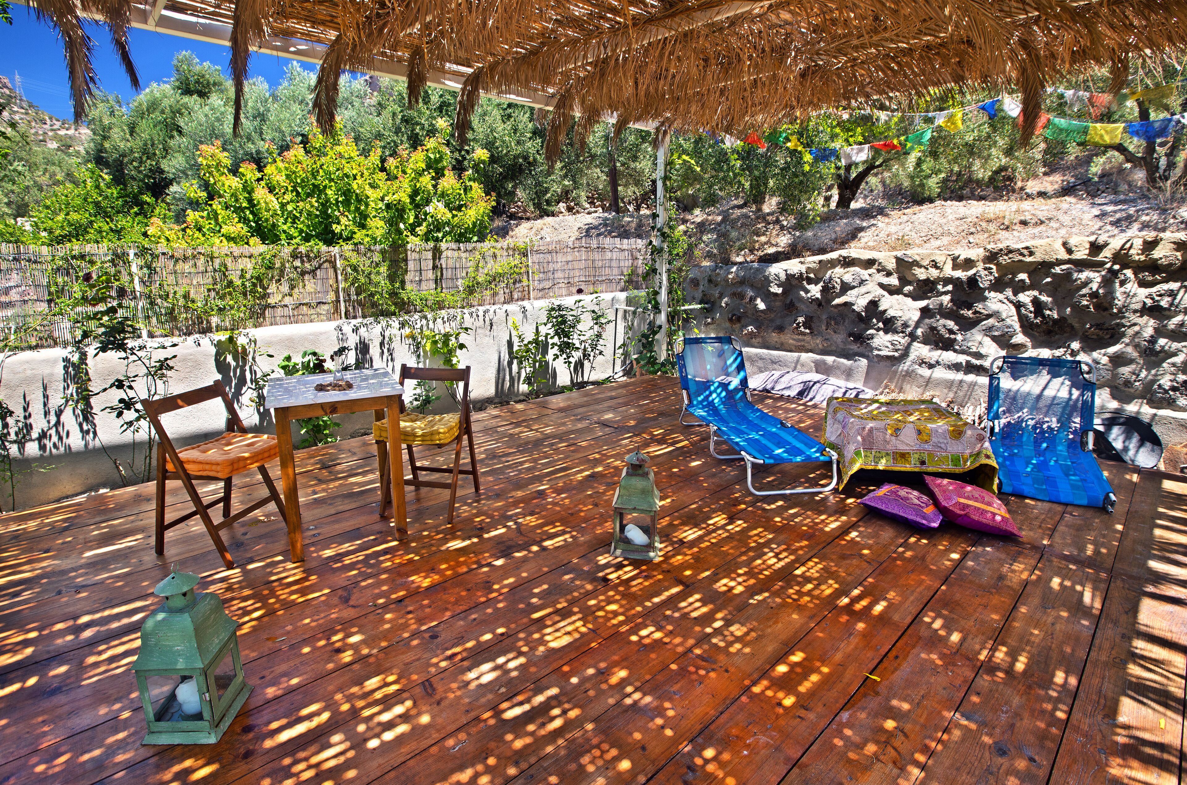 A wooden deck with a table, chairs, and a covered seating area.