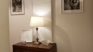 A room with a wooden dresser, a lamp, and two framed coffee-themed pictures on the wall.