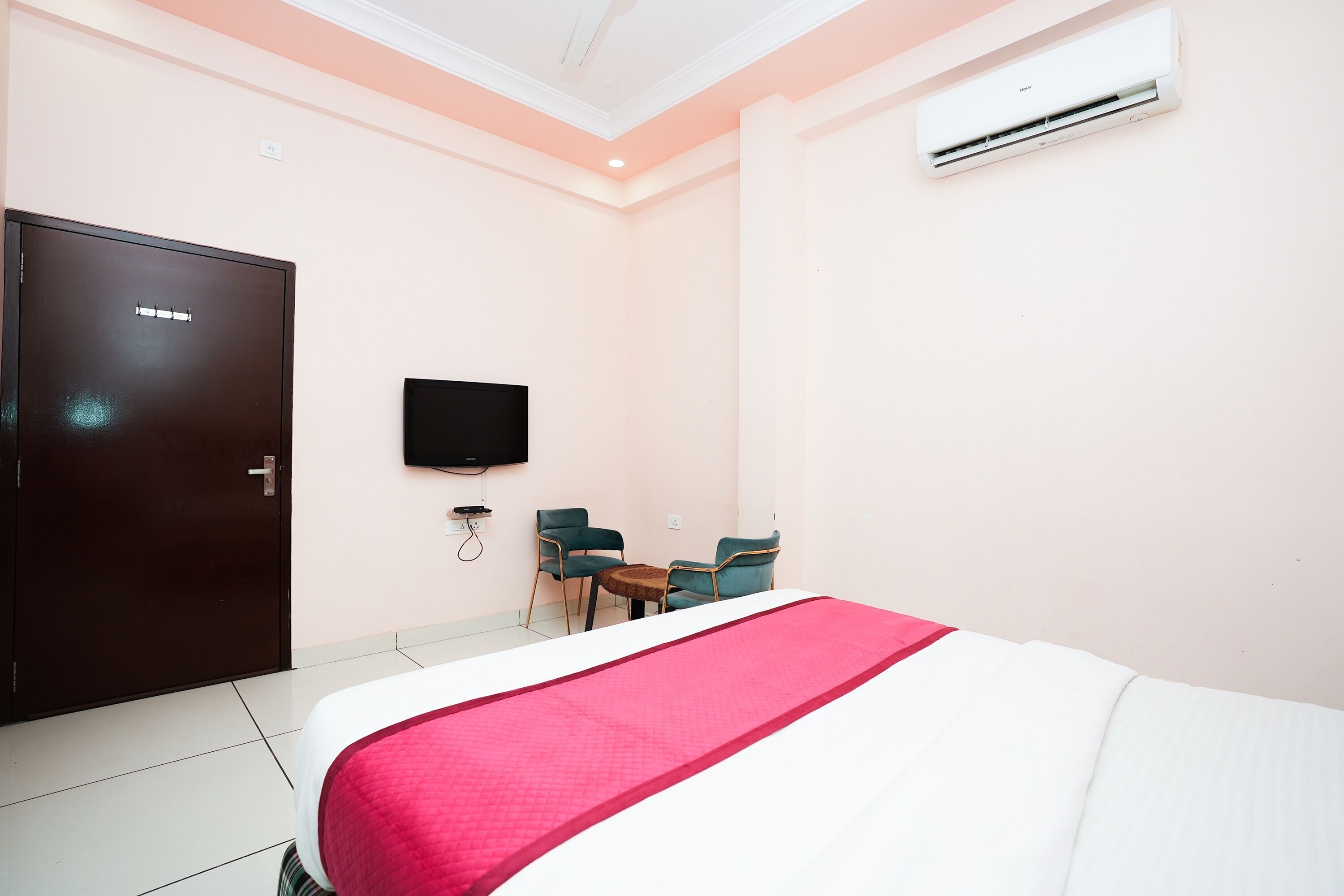 A hotel room with a bed, a TV mounted on the wall, a desk, and two chairs.
