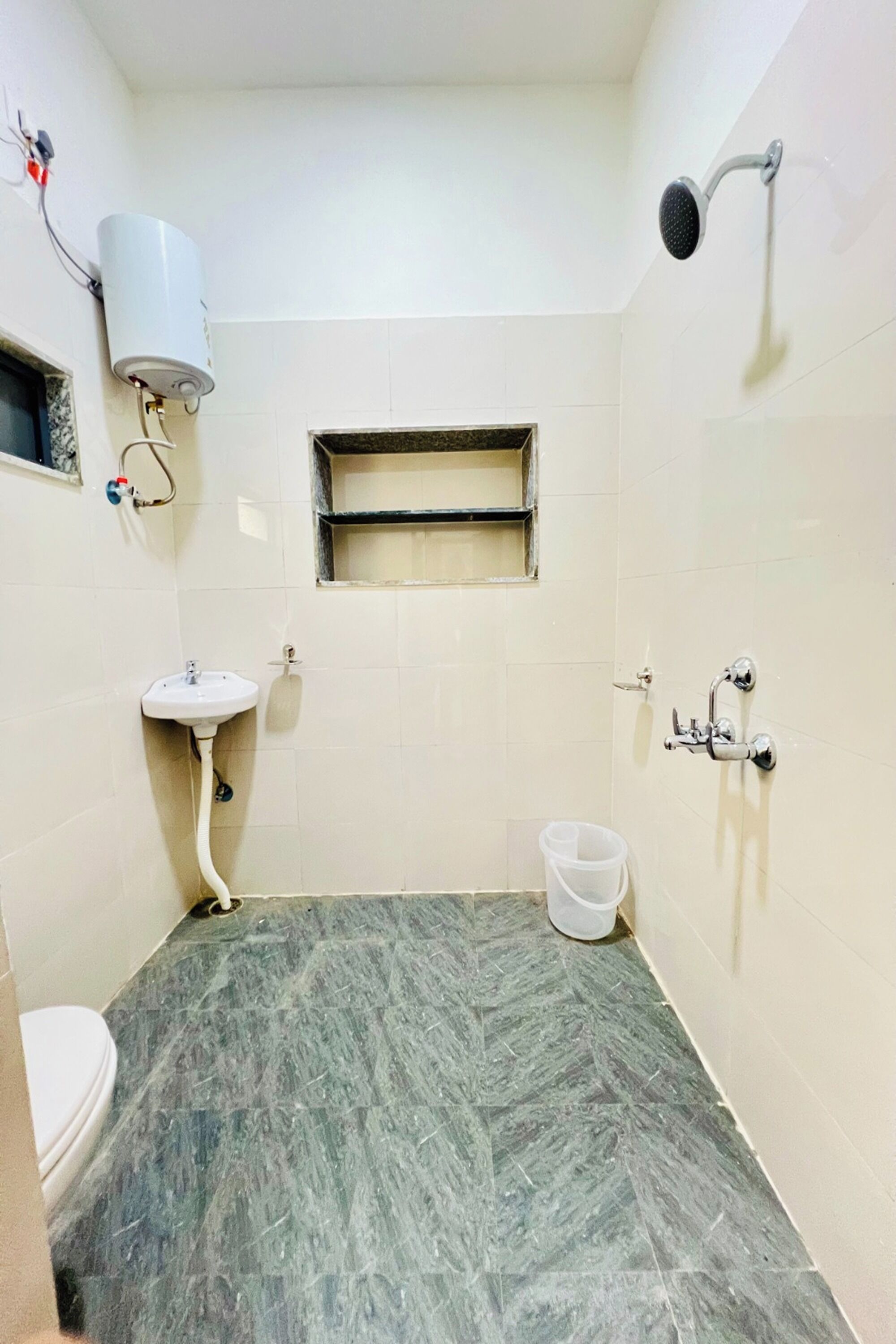 A bathroom with a sink, a shower, a toilet, and a small window.