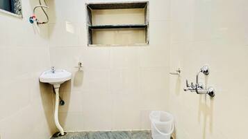 A bathroom with a sink, a shower, a toilet, and a small window.