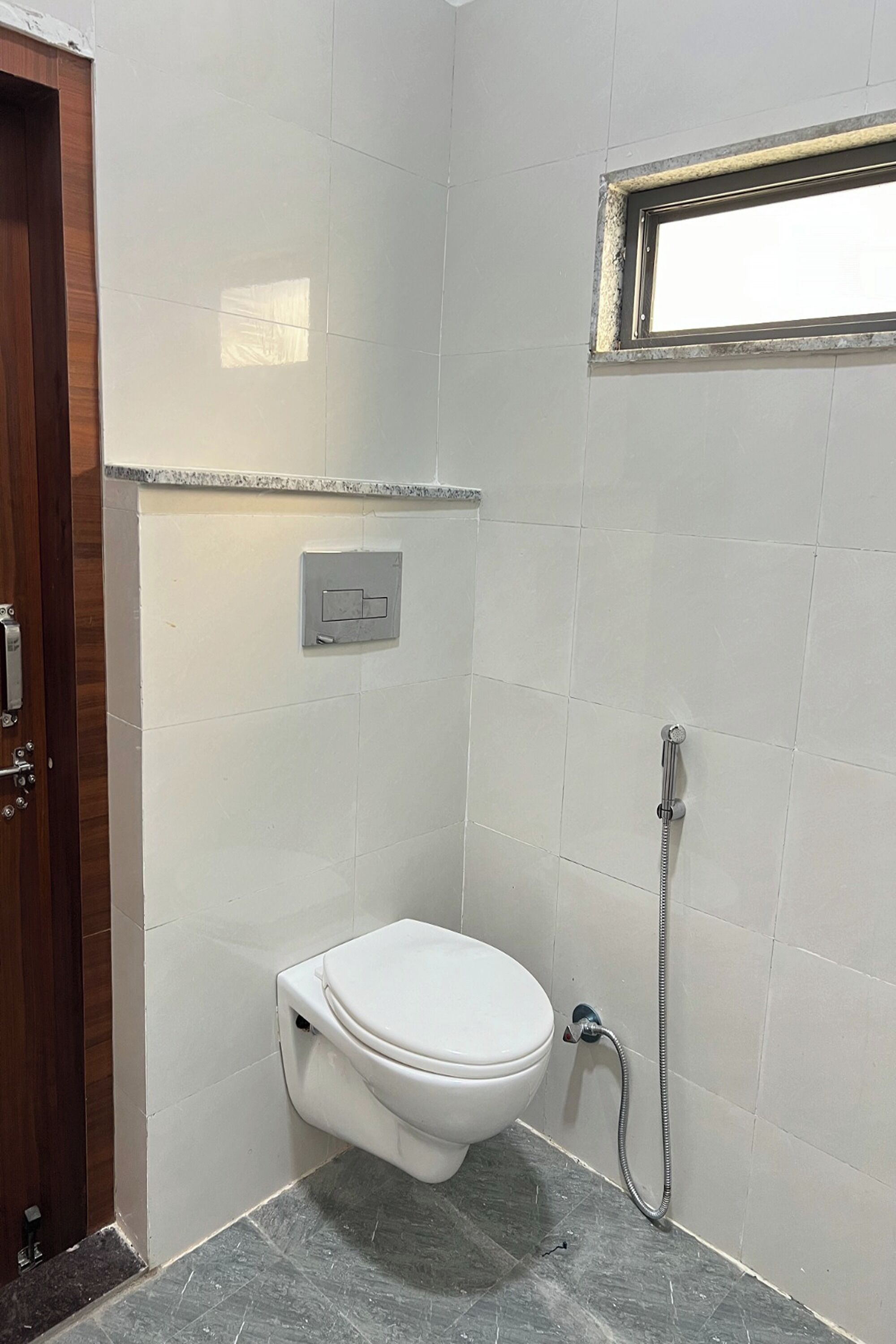 A bathroom with a toilet, a shower, and a small window.