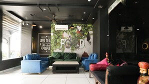 A modern living room with a green sofa, blue armchairs, and a black sofa. There is a wall mural with the text "PEOPLE WHO LOVE FOOD ARE ALWAYS the BEST PEOPLE" and a bicycle.