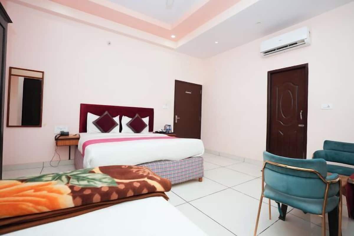 A hotel room with a bed, bedside table, chair, and an air conditioning unit.