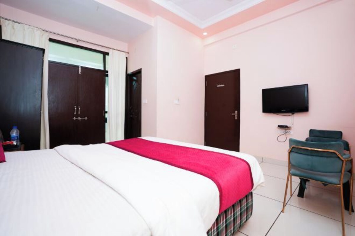 Una habitación de hotel con cama, televisión, armario y una silla.