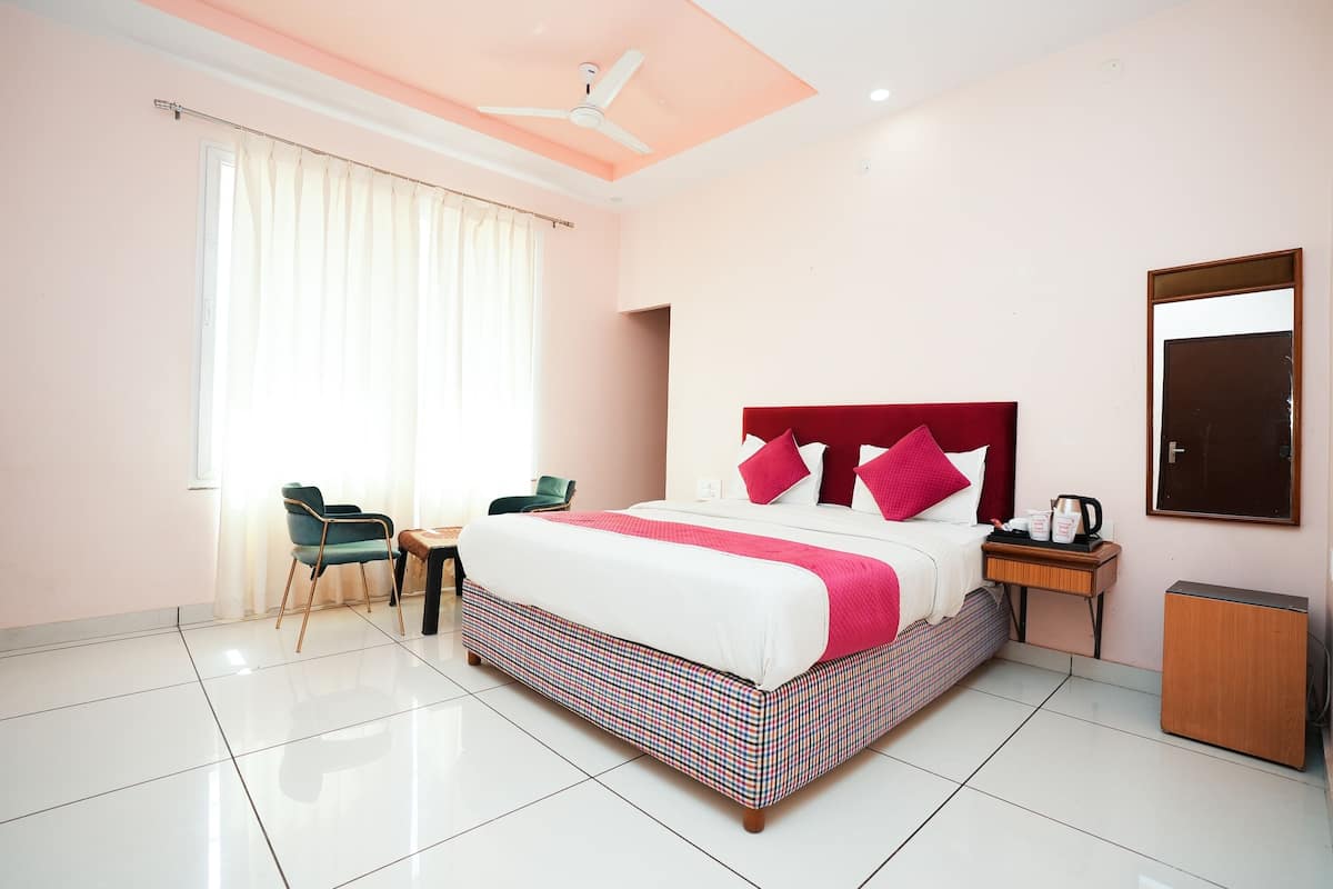 A hotel room with a large bed, a desk, a chair, a wardrobe, and a ceiling fan.