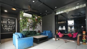 Un interior moderno con un sofá azul, divanes verde y azul, un banco de madera y una pared con un mural de 'Food'.