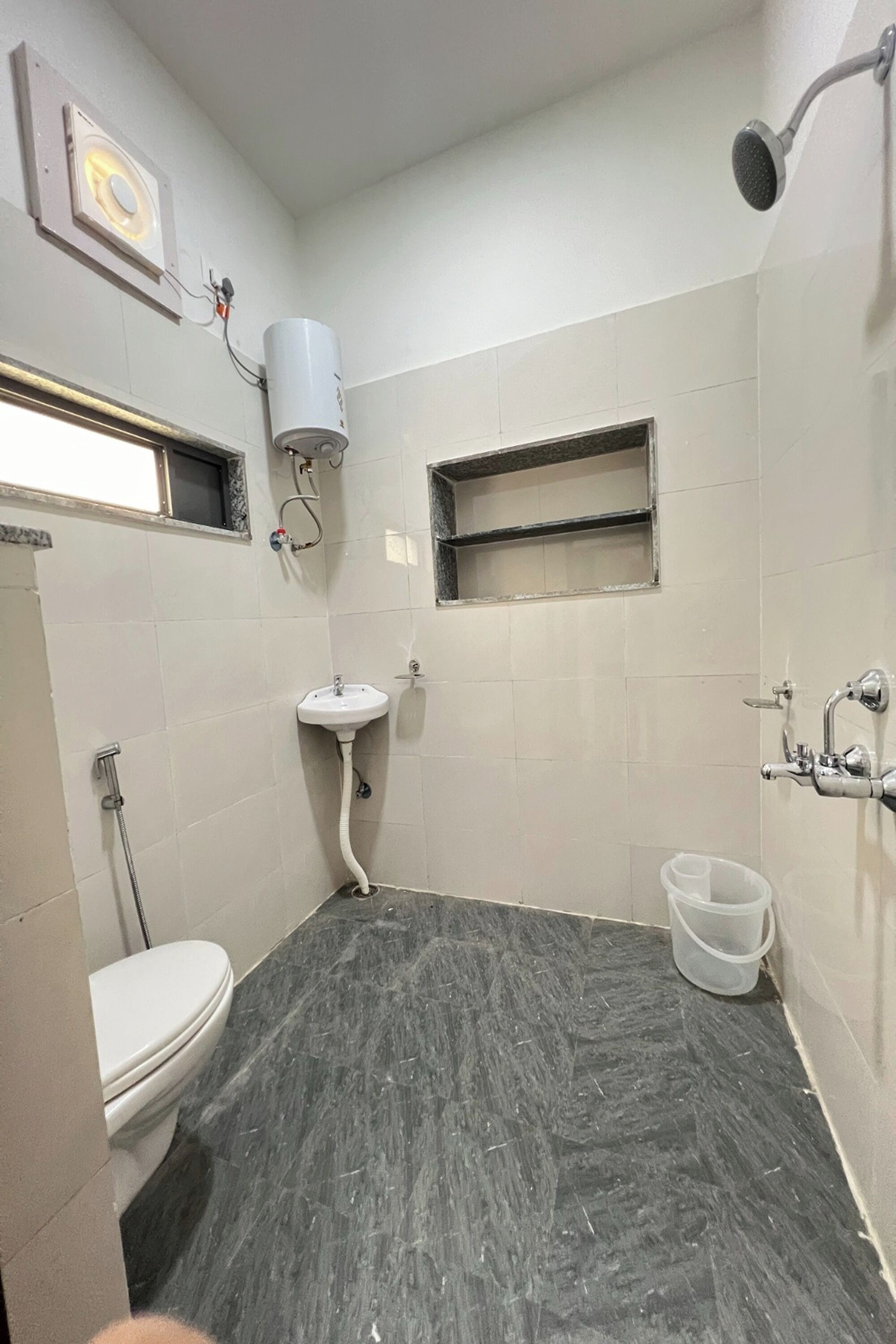Ein Badezimmer mit Toilette, Waschbecken, Dusche und einem kleinen Fenster.
