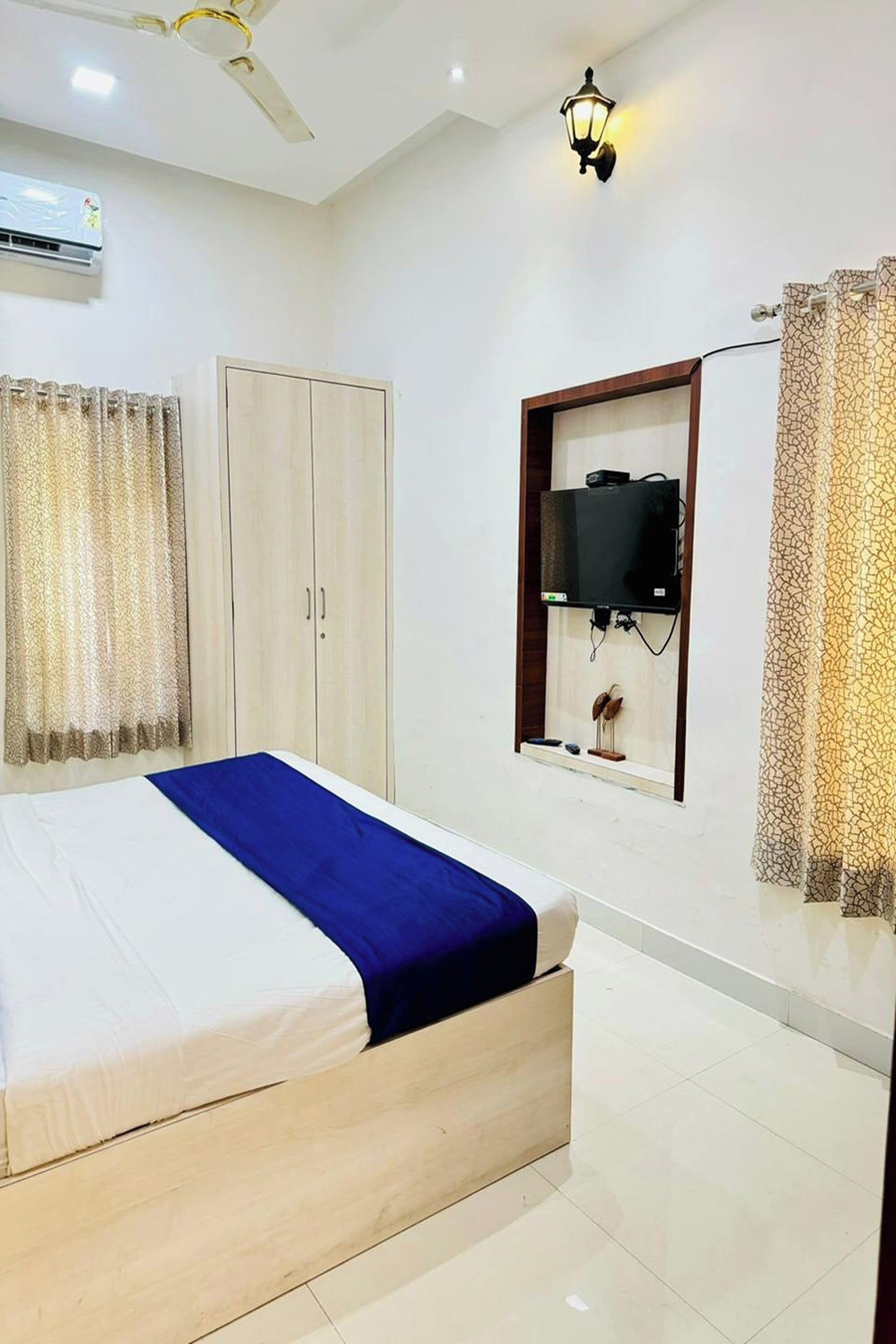 A bedroom with a bed, wardrobe, TV, and ceiling fan.