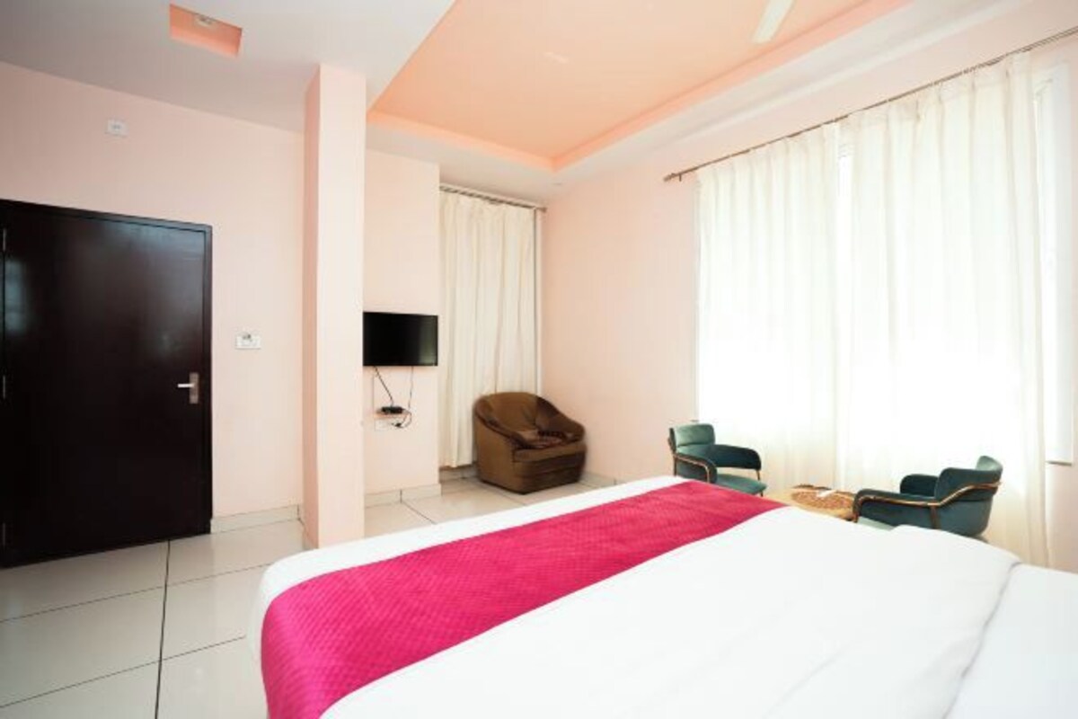 Una habitación de hotel con cama, televisión, silla y puerta.