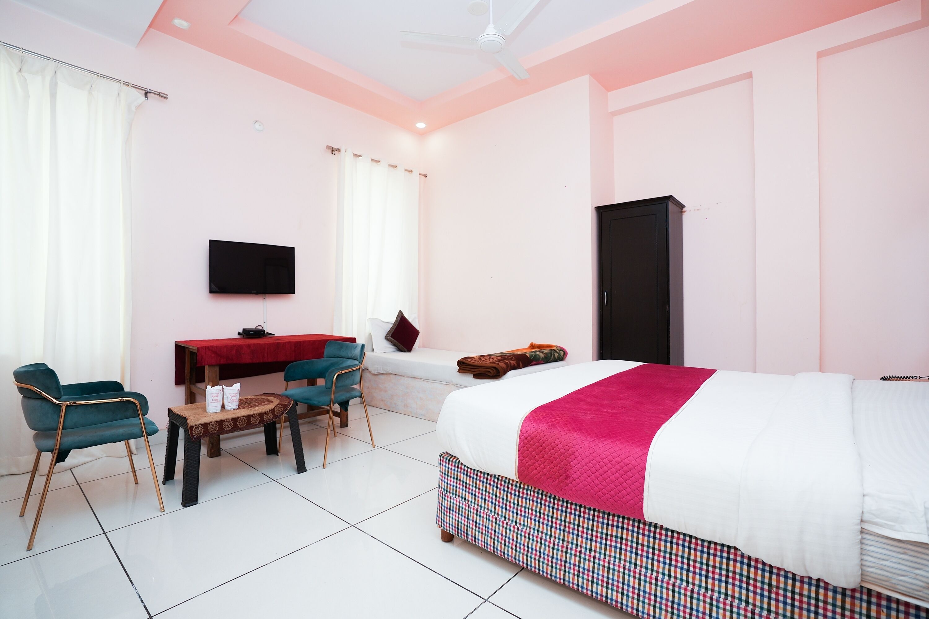 A hotel room with a bed, a desk, two chairs, a television, and a wardrobe.