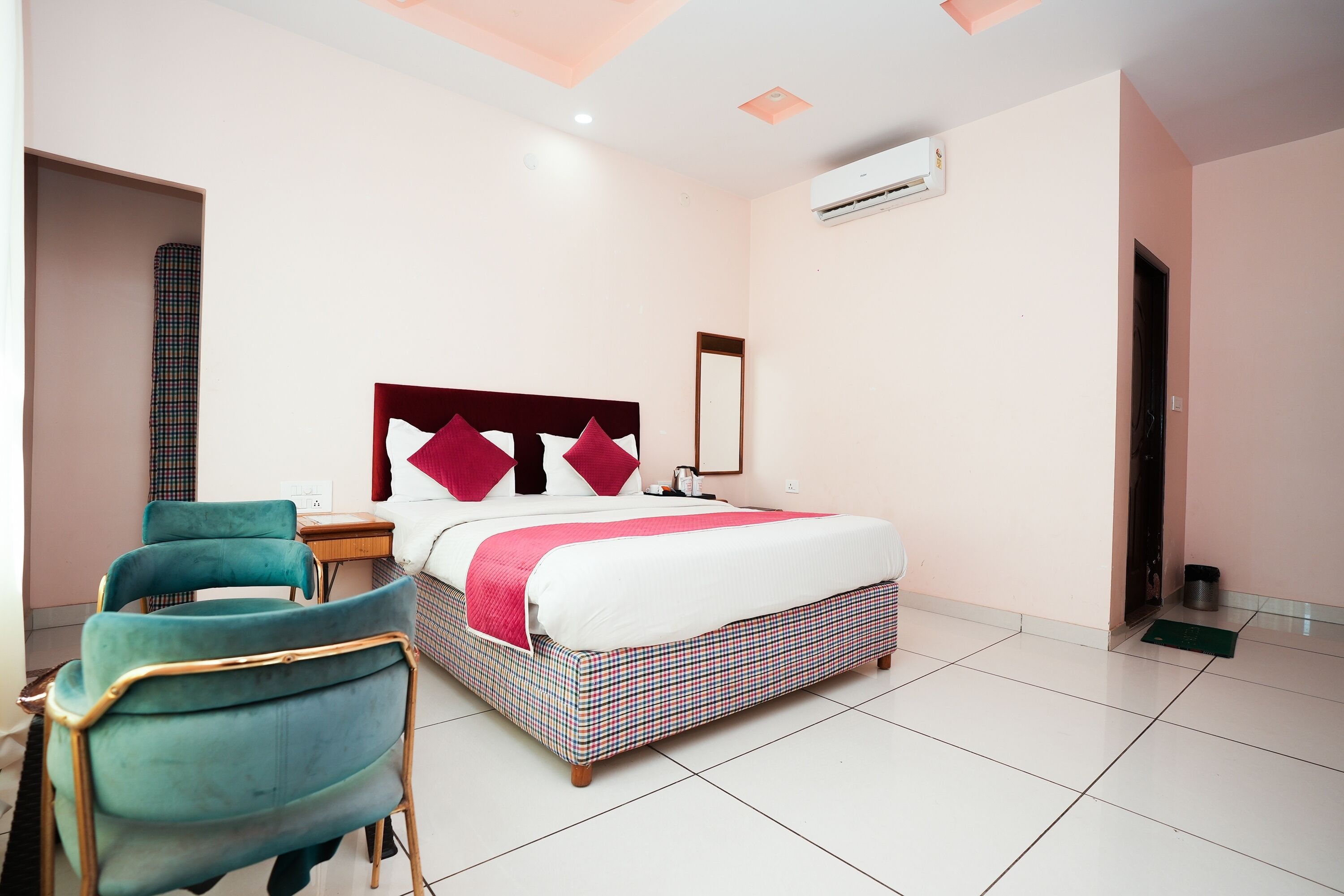 Ein Hotelzimmer mit einem Bett, einem Sessel, einem Nachttisch, einem Spiegel und einer Klimaanlage.