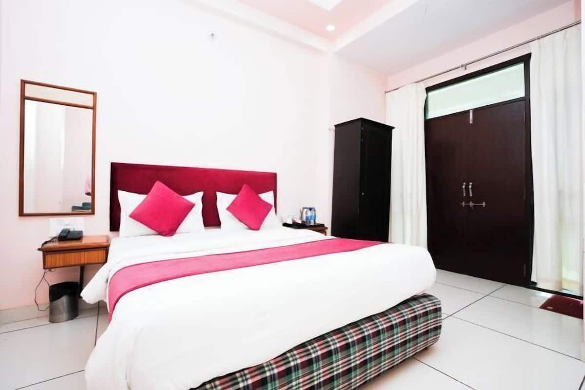 A hotel room with a bed, a nightstand, a wardrobe, and a mirror.
