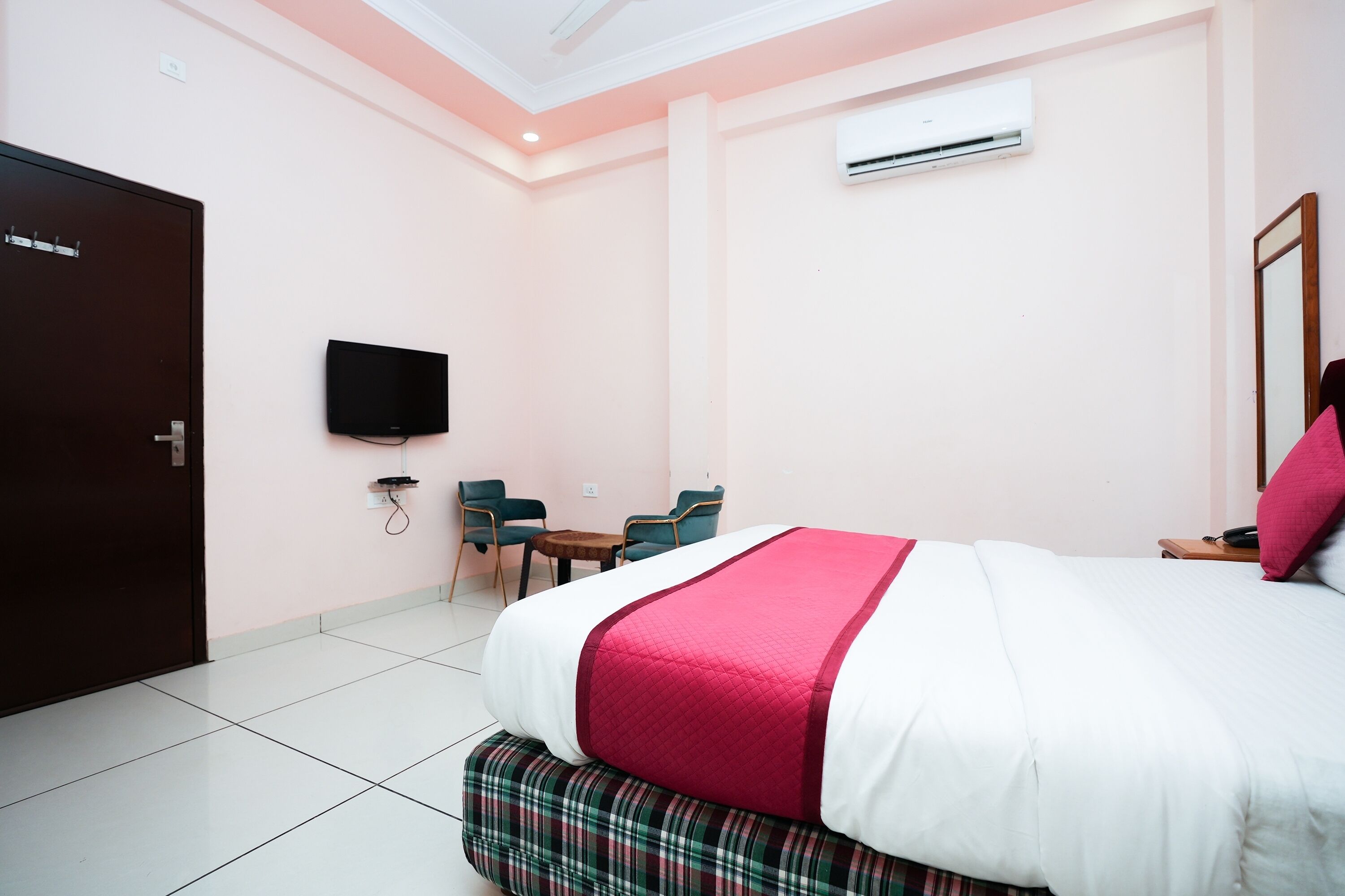 A hotel room with a bed, a television, a desk, and chairs.