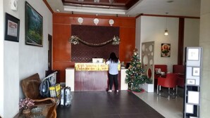 Een receptie met een bureau, een kerstboom en een vrouw erachter.