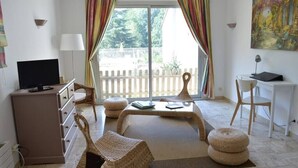A room with a sofa, a TV, a desk, and a painting. - Logis du Parc (Saint-Fulgent)