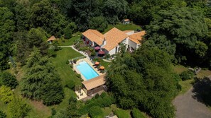 Vista aérea de una propiedad residencial con piscina, varias casas y abundante vegetación.