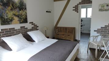 A bedroom with a bed, a wooden bench, a chair, and a painting on the wall.