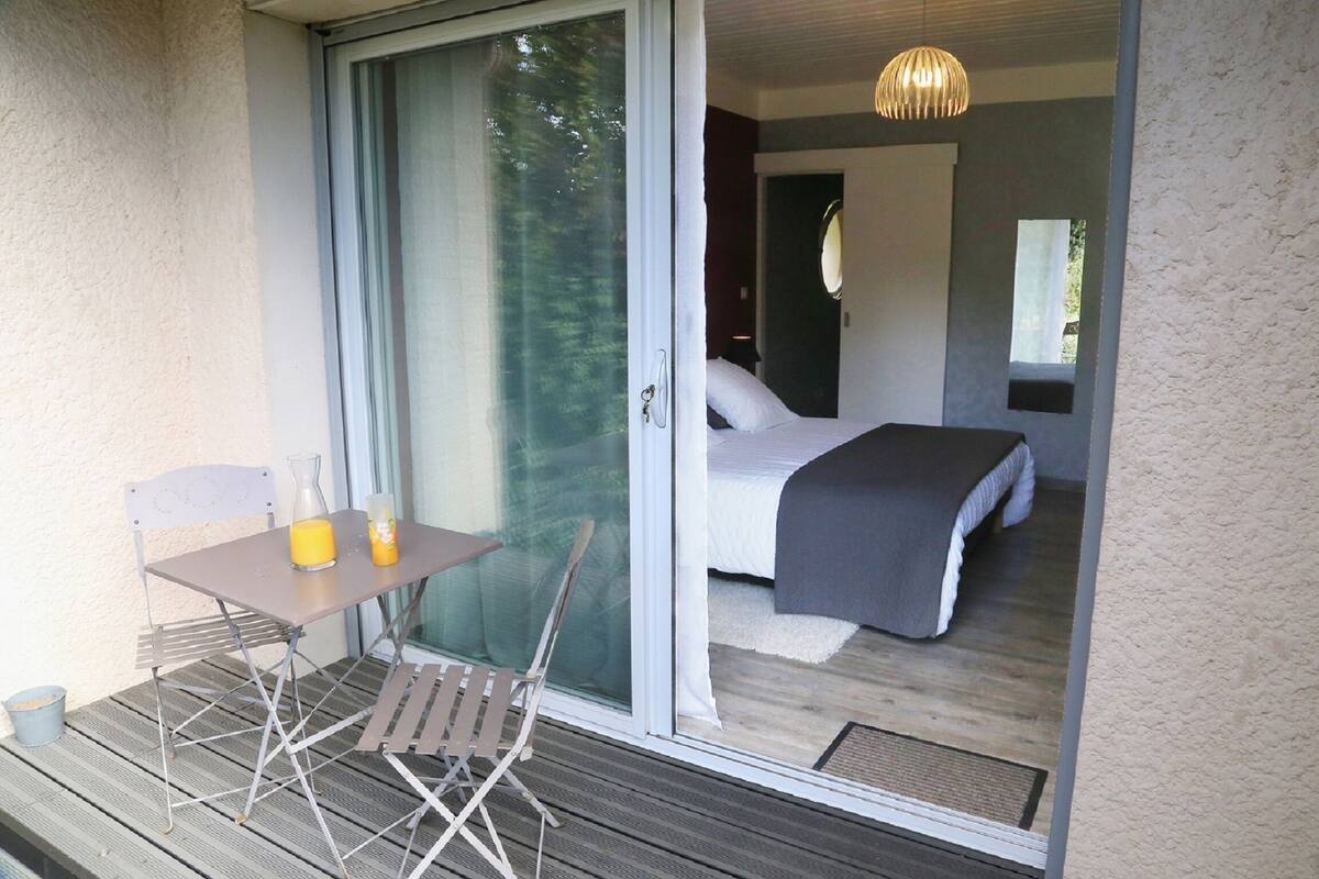 Un balcon avec une table, deux chaises et une bouteille de jus d’orange.