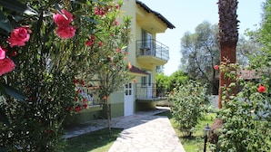 A two-story building with a balcony, a stone pathway, and lush greenery. - Dalyan Summer Life Apart Hotel (Ortaca)