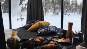Une table dressée pour le petit-déjeuner avec des croissants, un croissant coupé en deux, un petit bol, une tasse, une bouteille et un thermos.
