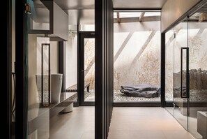 A modern interior with a glass partition, a bench, and a rock garden. - SCHLOSS Zermatt - CBD & Adaptogenic Spa and Sport Hotel (Zermatt)