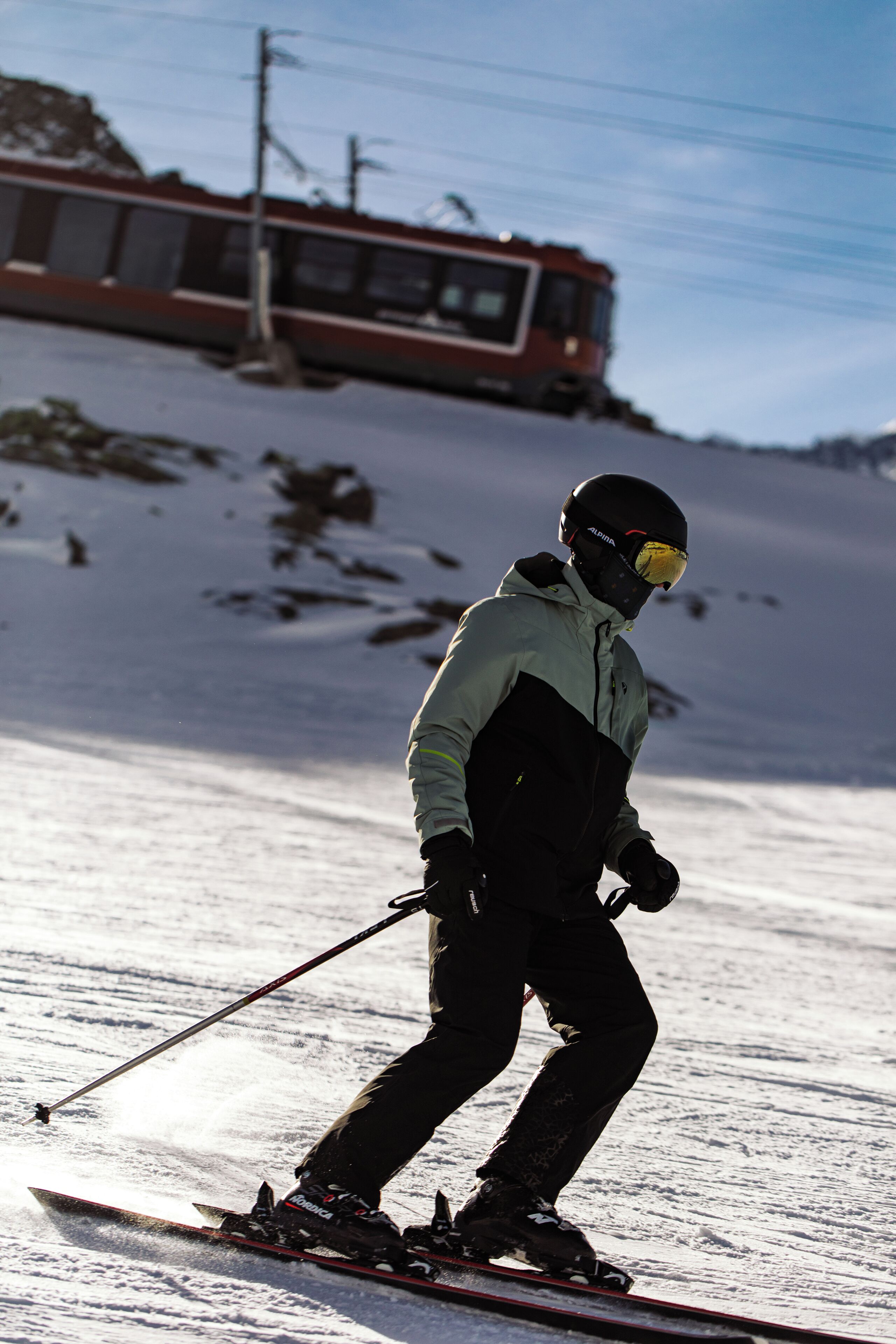 A person skiing on a snowy slope with a bus in the background.