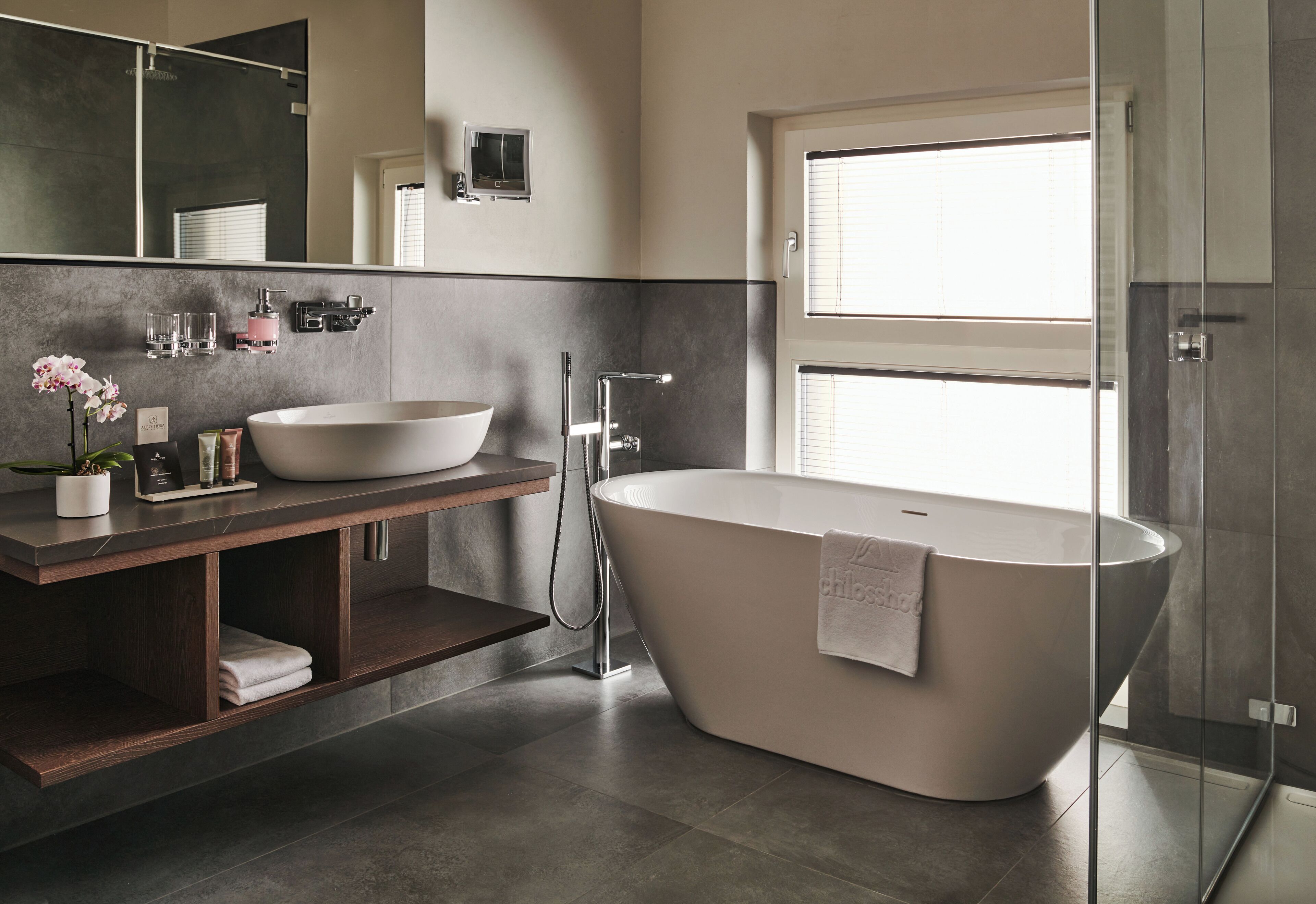 A modern bathroom with a freestanding bathtub, a large mirror, and a glass-enclosed shower.