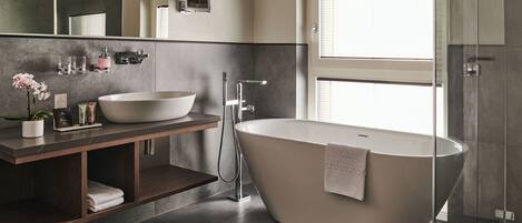 A modern bathroom with a freestanding bathtub, a large mirror, and a glass-enclosed shower.