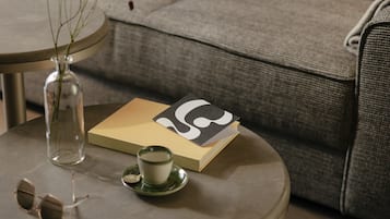 Una mesa redonda con un florero de vidrio, una taza y un par de gafas de sol.