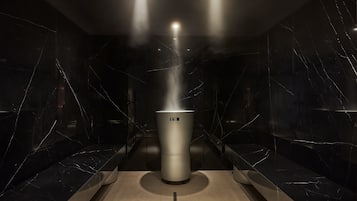 Una sauna dal design moderno, con un generatore di vapore centrale e pareti in marmo.
