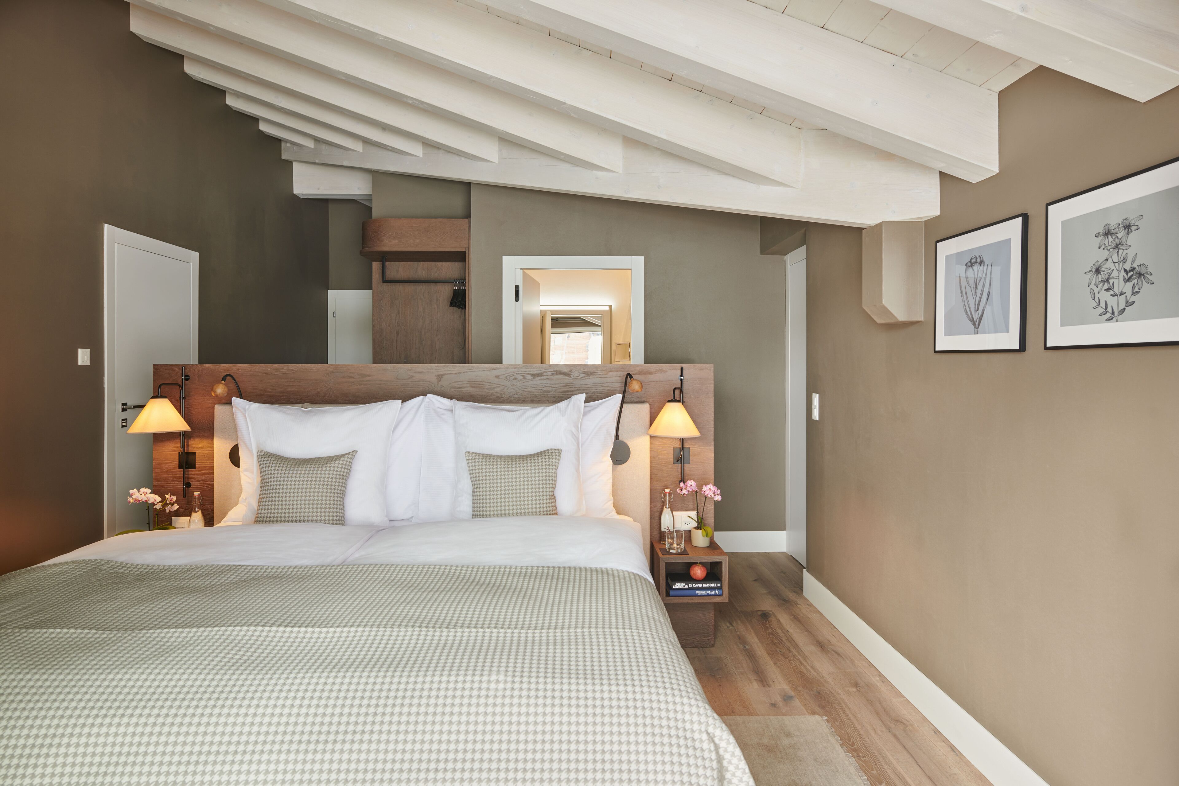 A bedroom with a large bed, wooden headboard, bedside lamps, and framed artwork on the wall.