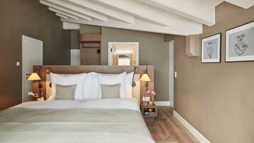 Camera da letto con un letto grande, una testiera in legno, lampade sui comodini e un quadro appeso al muro.
